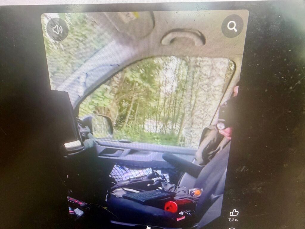 Kuvassa oikealla näkyy, kun poliisin siviiliauton takatilasta ilmeisesti poliisi osoittaa uteliasta kansalaista aseella.